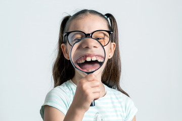 Little girl with a magnifying glass. The child looks like a happy monkey