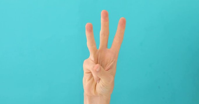 Closeup of isolated on blue adult female hand counting from 0 to 5. Woman shows fist fist, then one, two, three, four, five fingers