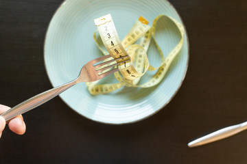 Diet concept - yelow measuring tape on fork