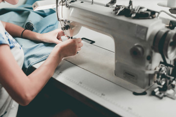 Dressmaker hands sews fabrics on sewing machine