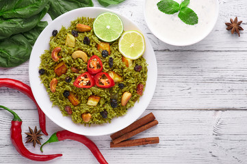Palak Paneer Biryani and Raita at white wooden background with decor. Palak Paneer Biryani is...