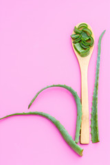 Medicinal plant aloe vera on a wooden spoon on a pink background