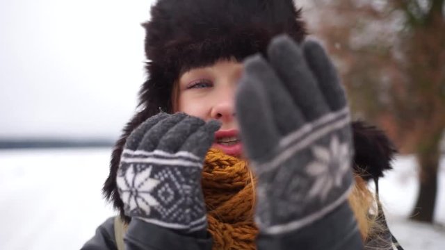 Beautiful girl freezes in the street. A girl in a hat with earflaps is on the street in winter. Russian beauty in a hat with earflaps.