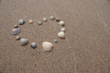 Fototapeta na wymiar Heart made of shells on the sand by the sea. Symbol of love.