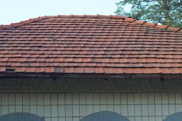 part of an old building with a brown tiled roof and gray wall