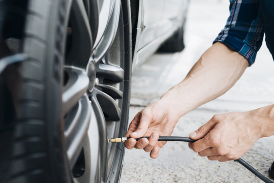 Man Using Air Pump On Car Wheel