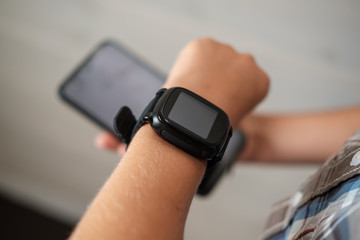 black smart watch on the boy's hand and black smartphone in the other hand
