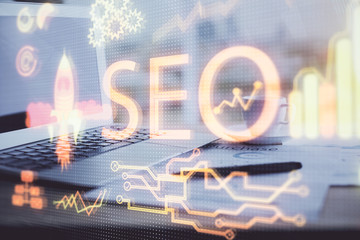 Double exposure of table with computer and seo drawing hologram. Search optimization concept.