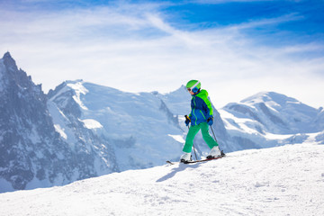 Naklejka na ściany i meble Little skier on the top of snowy peak at sunny day