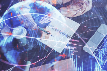 Forex graph on hand taking notes background. Concept of research. Double exposure
