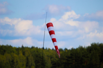 Wind sock with blue sky cloud and green tree.Wind direction indicator