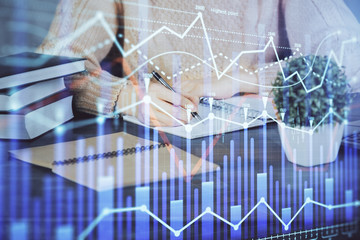 Forex graph on hand taking notes background. Concept of research. Double exposure