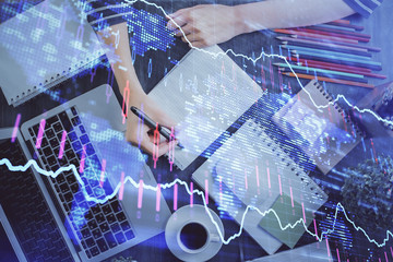 Financial forex graph drawn over hands taking notes background. Concept of research. Double exposure