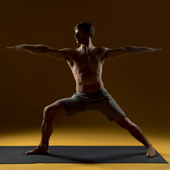 Fototapeta na wymiar Man practicing yoga positions on mat
