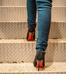 Women wearing jeans and wearing high heels are walking up the stairs.