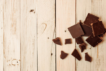 dark chocolate without sugar and gluten free for diabetics and allergics. Black chocolate broken into pieces lies on a white table in a rustic style. Copy space.