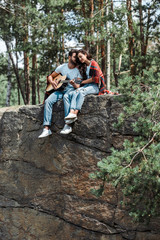 Naklejka na ściany i meble bearded man playing acoustic guitar near attractive woman in woods