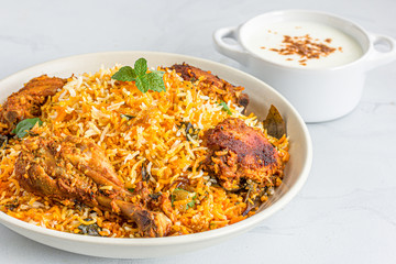 Chicken Biryani with Raita and Onion on White Background. Traditional Indian One Pot Rice and Chicken Dish..