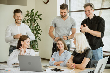 Obraz premium A young member of the student team achieves success. The remaining students applaud her laugh and enjoy her success