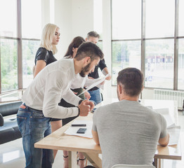 The young employee offers his own solution to the boss while the rest of the team is working
