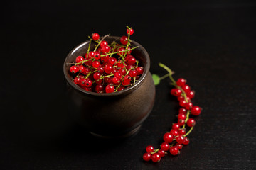 Red currants in a mug on a dark background. Strongly red delicious currants. A delicious background for use in the media.
