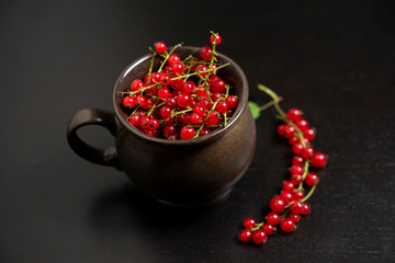 Red currants in a mug on a dark background. Strongly red delicious currants. A delicious background for use in the media.