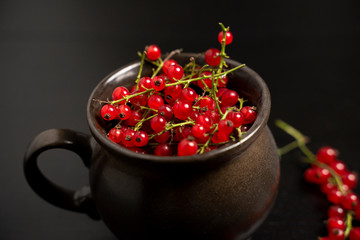 Red currants in a mug on a dark background. Strongly red delicious currants. A delicious background for use in the media.