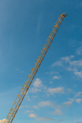 Tall yellow crane on a sunny blue sky.