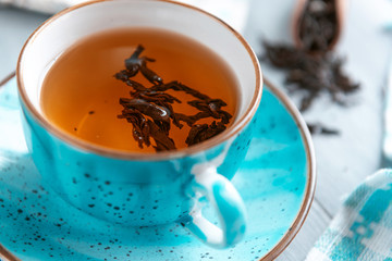 composition still life of a mug with hot leaf tea with berries and autumn leaves on a wooden surface