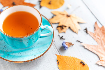 composition still life of a mug with hot leaf tea with berries and autumn leaves on a wooden surface