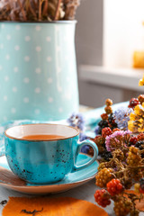 composition still life of a mug with hot leaf tea with berries and autumn leaves on a wooden surface