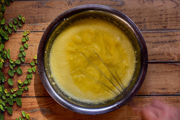 Bowl with ingredients to make a banana bread on a wooden surface with green leaves