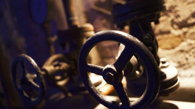 Water pipe chamber valves in a old shady dark basement, close up