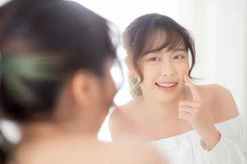 Beautiful face young asian woman with happy smiling and looking mirror, makeup of beauty facial girl with skincare and cosmetic treatment, refresh of female and clean for charming, healthy concept.