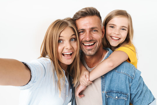 Image of adorable caucasian family woman and man with little girl smiling and taking selfie photo together