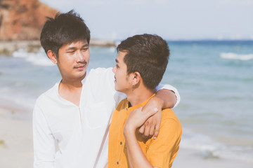 Obraz premium Homosexual portrait young asian couple standing hug together on beach in summer, asia gay going tourism for leisure and relax with romantic and happiness in vacation at sea, LGBT concept.