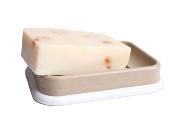 Natural organic soap without packaging in a soap dish isolated on white.