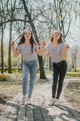 Obraz premium Friendship day. Lifestyle image of best friend girls in spring summer city street. Two Teenage girls having fun in the park