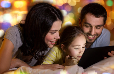 people and family concept - happy mother, father and little daughter with tablet pc computer in bed at night at home