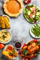 Thanksgiving dinner table with roasted whole chicken or turkey, green beans, mashed potatoes, cranberry sauce and grilled autumn vegetables. Top view, frame.