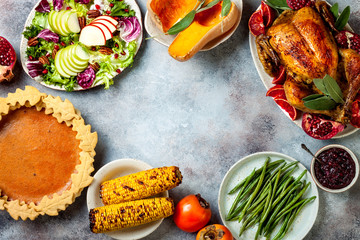 Thanksgiving dinner table with roasted whole chicken or turkey, green beans, mashed potatoes, cranberry sauce and grilled autumn vegetables. Top view, frame.