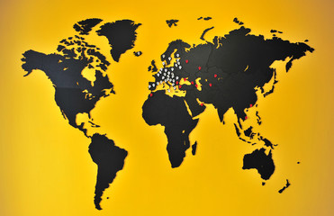 World map with pins on the yellow wall