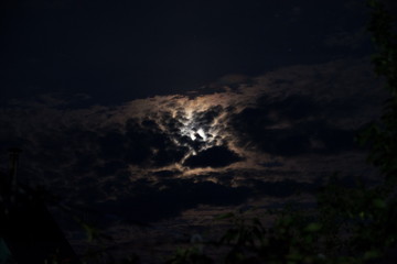 moon in the black sky peeps out of the clouds