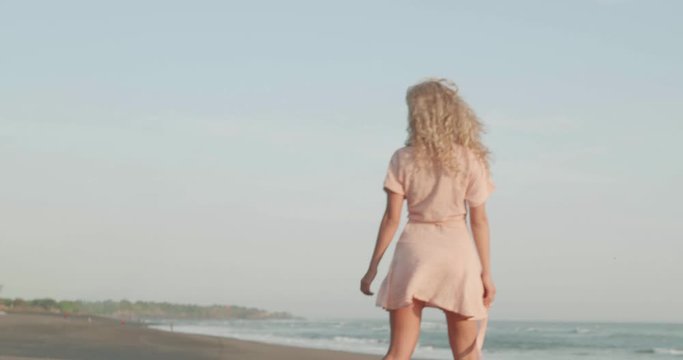 Pretty happy girl in dress relaxing on the tropical beach. Young woman drawing heart on the sand during sunny summer day - video in slow motion