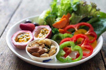 Fruit and Vegetable salad on a white plate on a wooden table