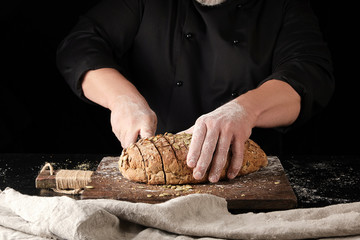 baker in black uniform cuts a knife into slices of rye bread © nndanko