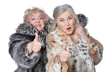 Portrait of senior women in fur coats with thumbs up