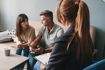 Photo of caucasian casual couple having conversation with psychologist on therapy session in room