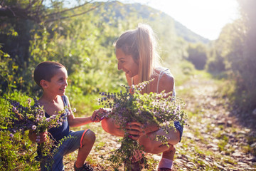 Mother and son picking flowers / herbs in nature.