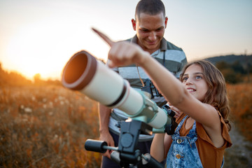 Father and daughter observing the sky with a telescope.